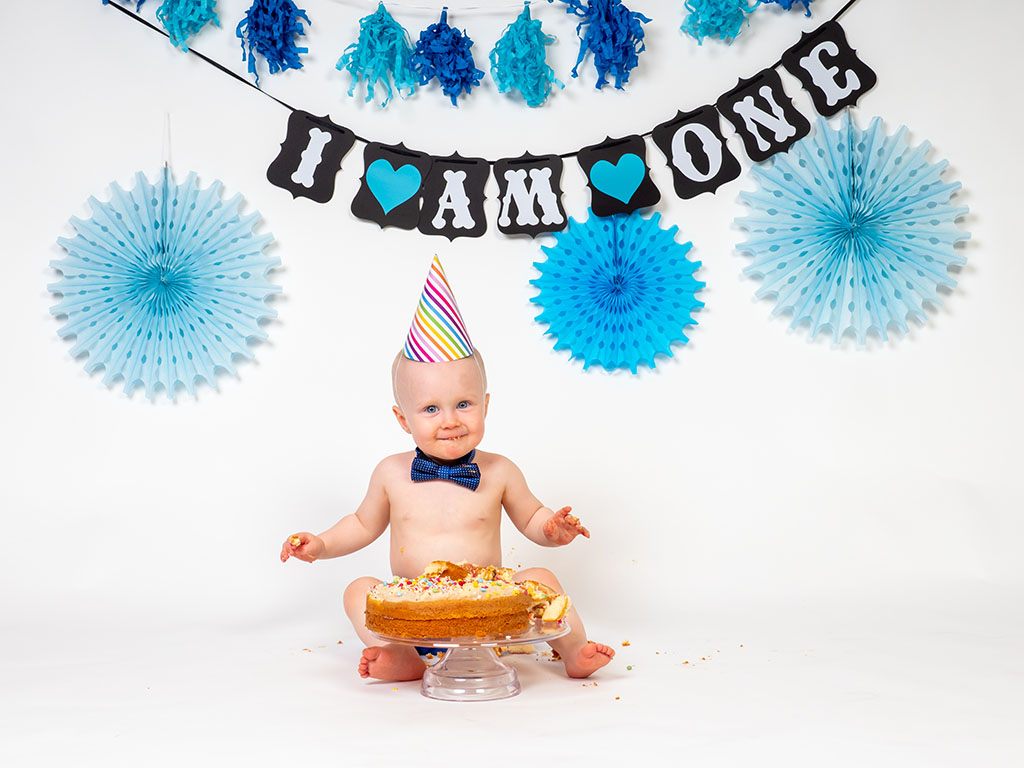 baby boy sitting with cake smashed on cake stand taken by cake smash photographer in Braintree